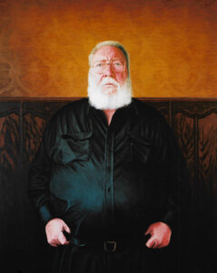 Oil on canvas portrait painting by Josonia Palaitis depicting journalist Paddy McGuiness standing and wearing a black shirt with his thumbs tucked into his belt wearing his glasses and sporting a big white beard